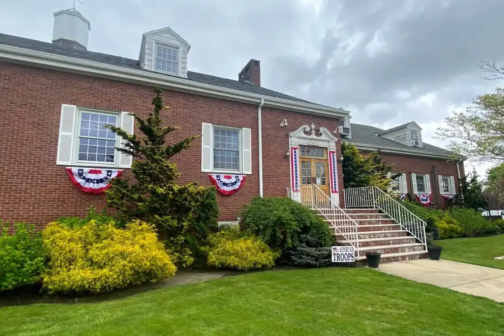 East Rockaway Village Hall, a red brick building with bunting and a front lawn
