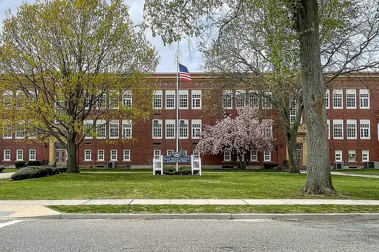 East Street Elementary School, a long red brick building behind a lawn with blooming trees in Hicksville