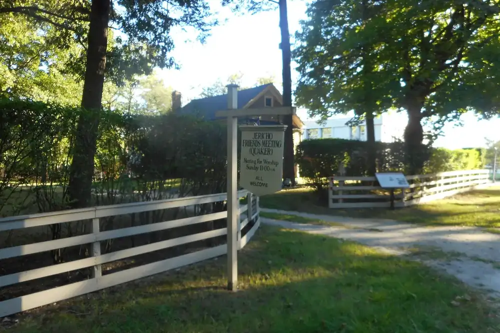 Historic Jericho Friends Meetinghouse grounds with a white wooden fence and path in Jericho, New York