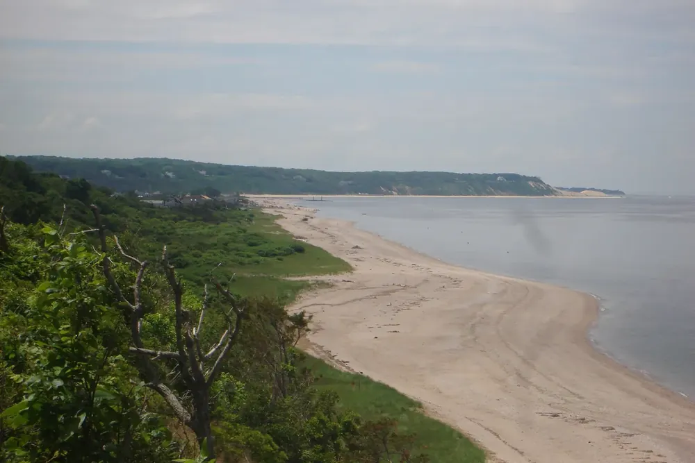 Sandy beach below green bluffs along the water of Long Island Sound in Miller Place, New York