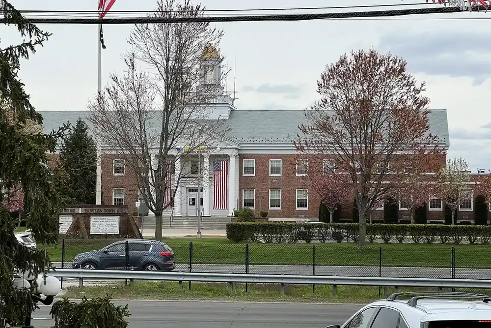 Babylon Town Hall, a red brick building with a white cupola and flag, in North Lindenhurst, New York