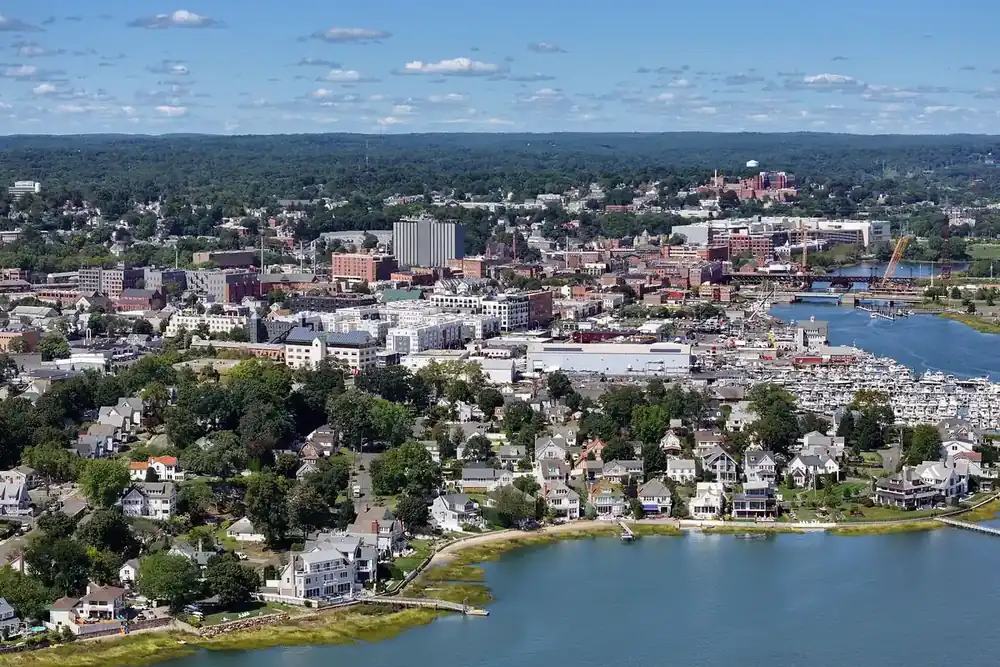 Aerial view of Norwalk, Connecticut, with waterfront homes, a busy marina and downtown beyond