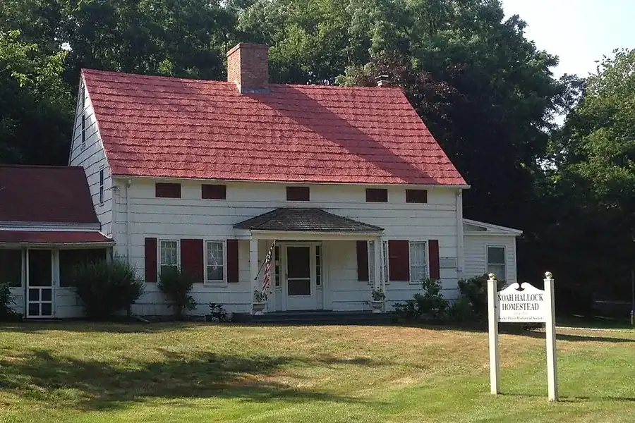 Noah Hallock Homestead, a white historic farmhouse with a red roof and a small sign in Rocky Point