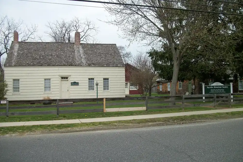Edwards Homestead, a small pale historic house with a shingled roof in Sayville, New York