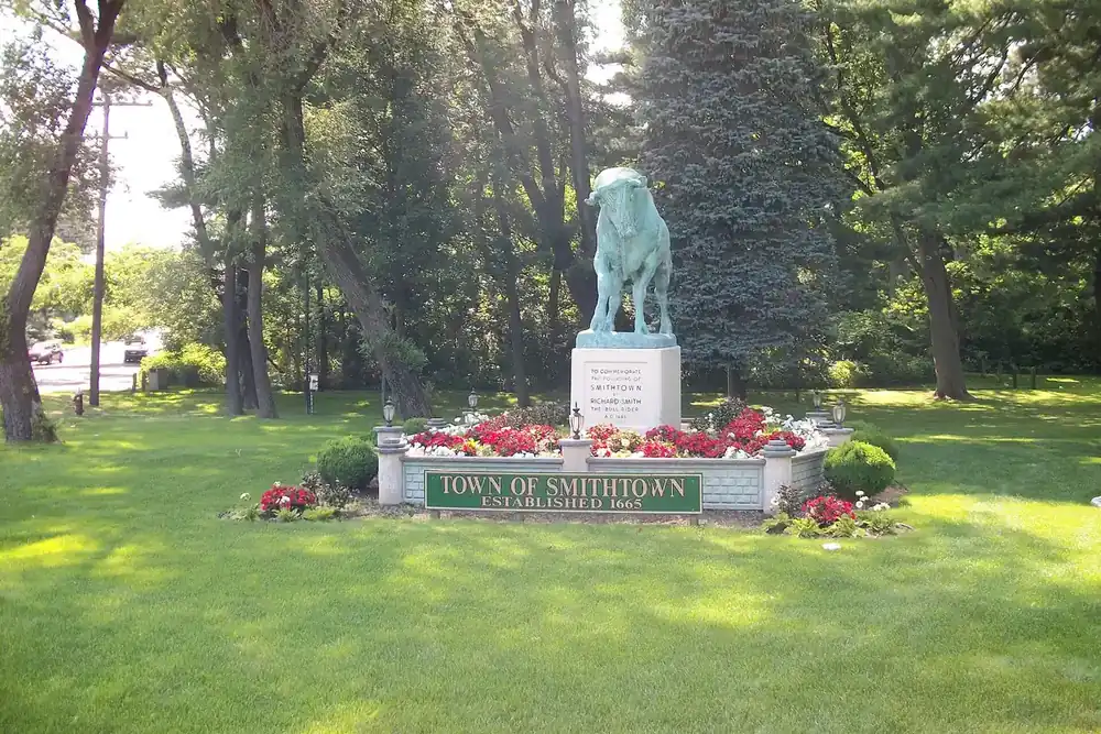 Smithtown Bull statue and flower beds beside a Town of Smithtown sign in Smithtown, New York