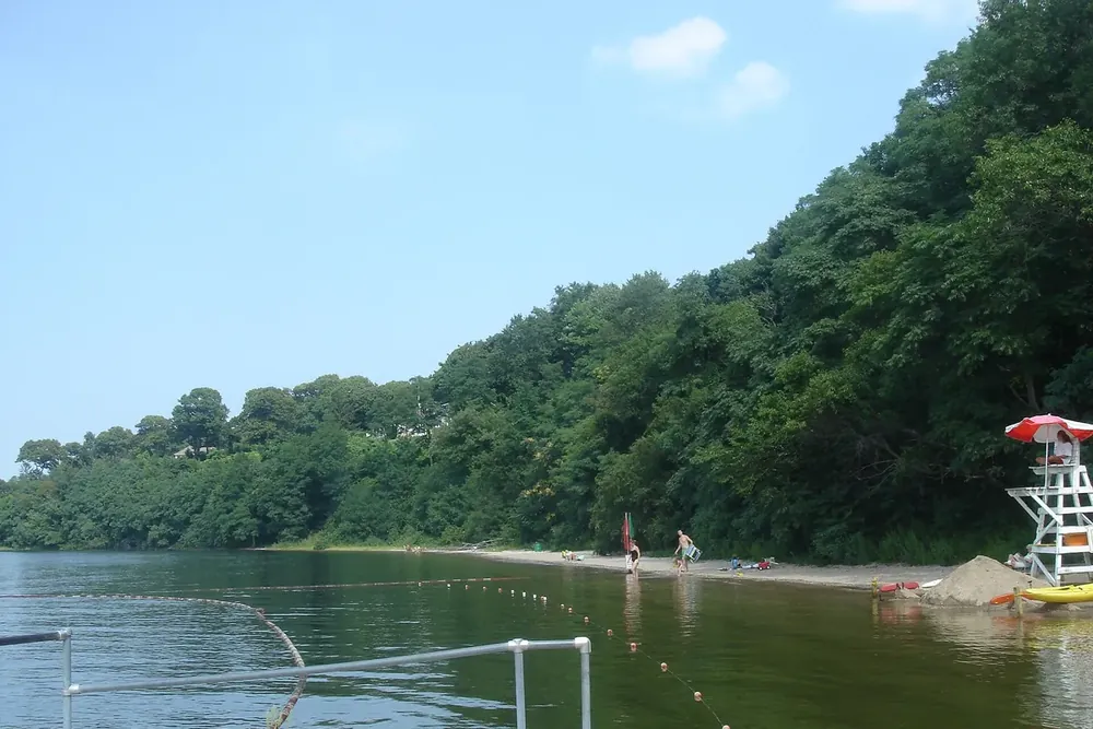 Wooded bluff above a sandy swimming beach with a lifeguard chair in Stony Brook, New York