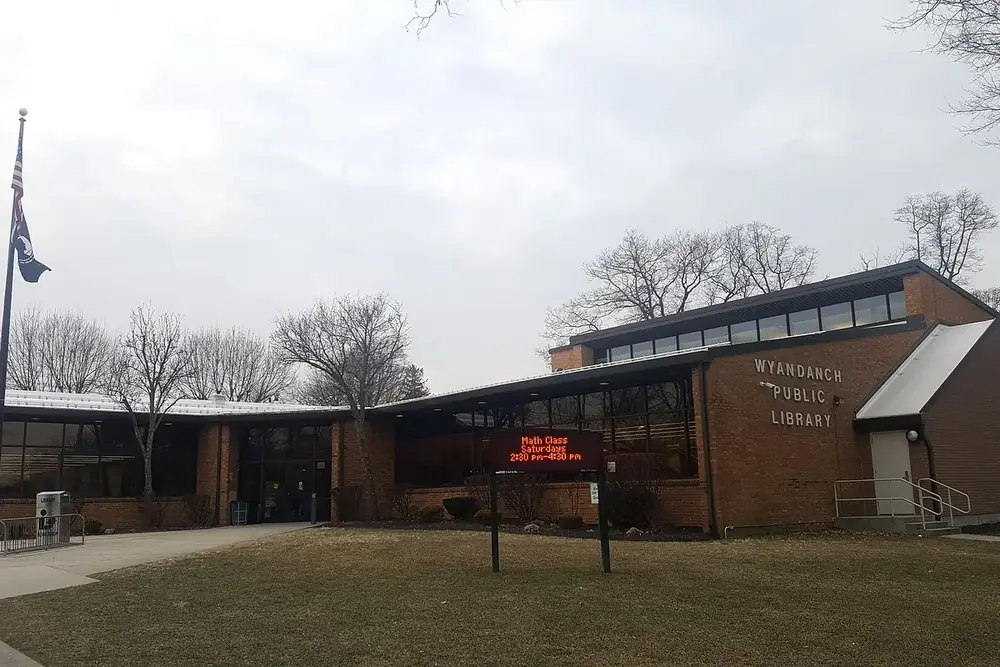 Wyandanch Public Library, a low brick building with a flag and lawn in Wyandanch, New York